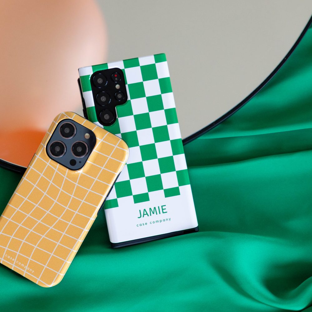 Due custodie rigide: una a quadri gialli per iPhone e una a blocchi verdi con il nome Jamie
